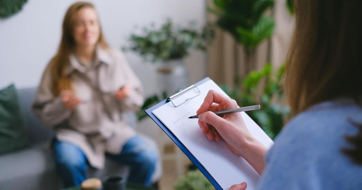 Counselor writing client notes during an intake session