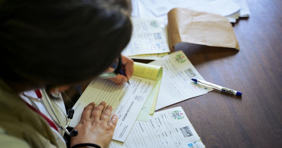 Therapist sitting at desk reviewing paperwork and billing documents